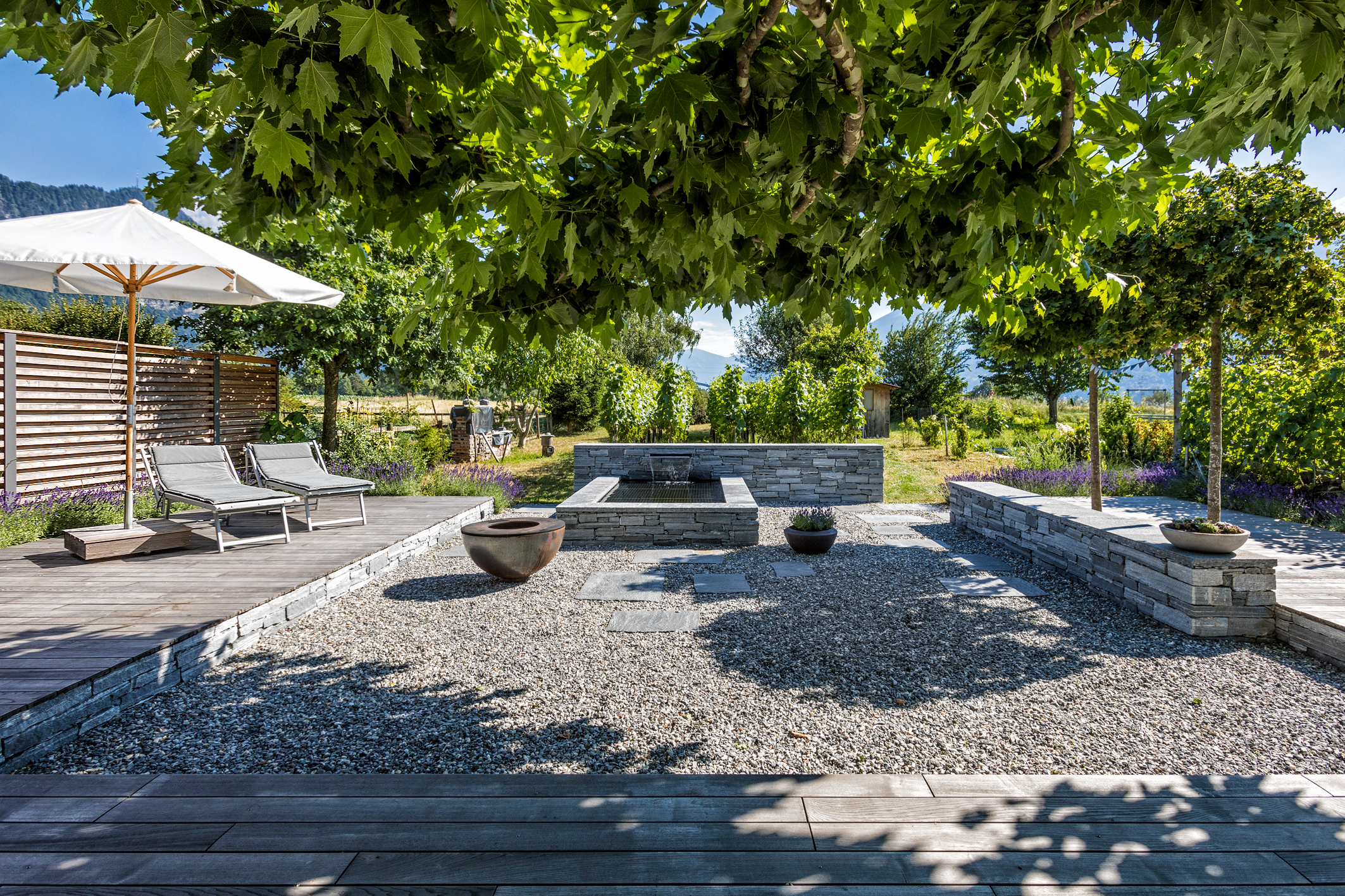 Weindegustationen unter den Baumkronen und neben dem Brunnen - Aussenraumgestaltung von PARC'S