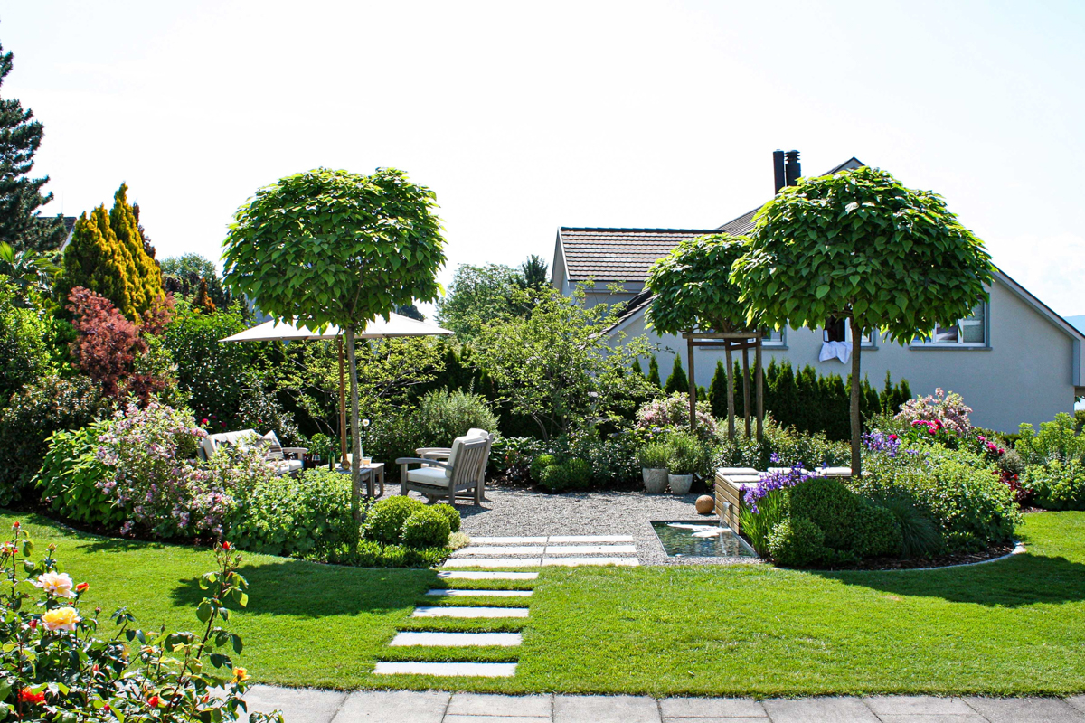 Die Gartenumgestaltung setzt den Sitzplatz in den Fokus und lässt angenehme Stunden durch den Brunnen entstehen.